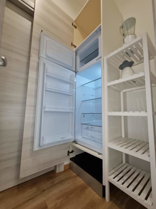 Otvoren hladnjak u Raymihome apartmanu u Torinu, s vidljivim bijelim policama i drvenim podom