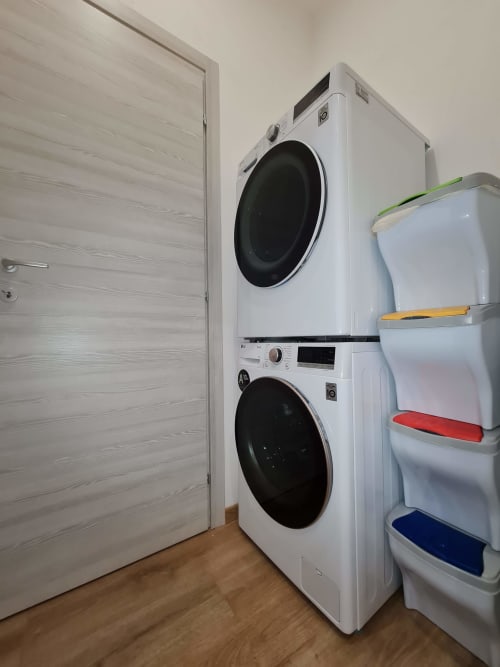 Praonica s naslaganim belim mašinama za pranje i kutijama za pohranu u apartmanu Raymihome u Torinu