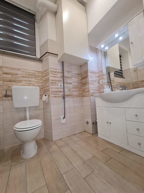 Moderna kupaonica u apartmanu Raymihome u Torinu s bijelom opremom, podovima od keramičkih pločica sa drvenim uzorkom i tušem bez kabine