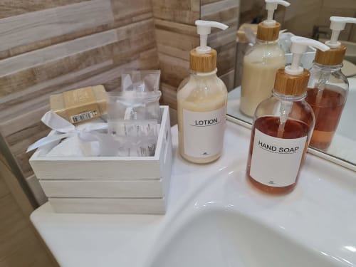 Kupaonske potrepštine u apartmanu Raymihome u Torinu, uključujući losion, tečni sapun i toaletne pripreme s drvenima pumpama.