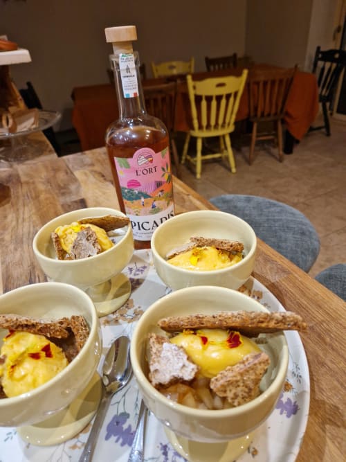 Assiettes de petit-déjeuner gourmand avec œufs et pâté à la Maisonaurinko B&B à Thénon, France, accompagnées d'un vin L'Ort Picard.