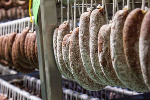 Embutidos curados colgados en hileras en una carnicería tradicional española de Mérida