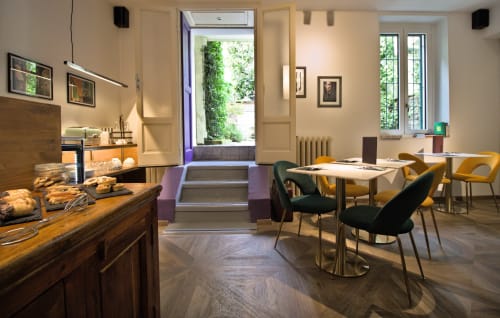 Sala colazione Porta Tosa a Milano con tavoli in legno, sedie gialle e vista sul giardino attraverso le porte in vetro
