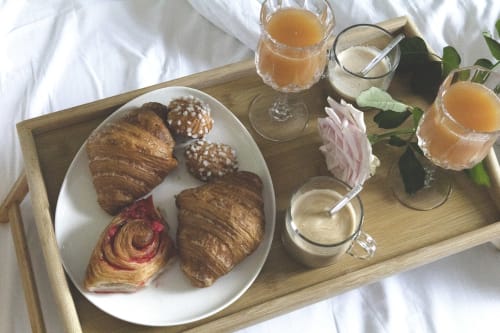 Elegant breakfast in bed at Montmartre Romantic B&B Paris: croissants, pastries, coffee, juice and fresh rose on wooden tray