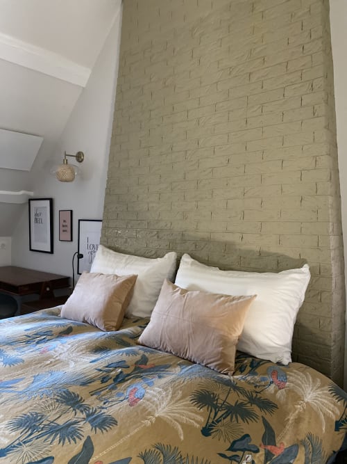 Chambre à La Guirtelle B&B à Lainsecq avec mur de briques crème, literie motifs et oreillers blancs.