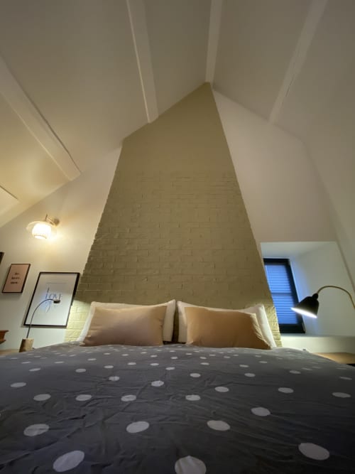 Chambre moderne avec mur de briques apparentes à La Guirtelle B&B, literie et oreillers à pois