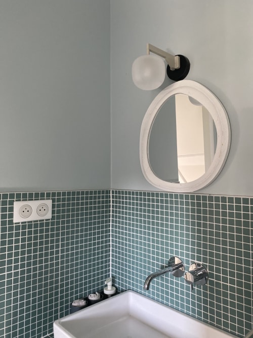 Coin de salle de bain du B&B La Guirtelle avec miroir rond, lavabo blanc, carrelage vert et applique murale