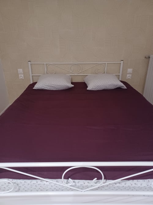 Chambre de cottage à l'Accolade Hotel à Châteaudun avec lit en bourgogne, tête de lit en métal blanc et coussins décor