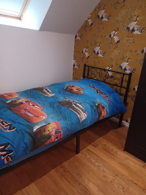 Chambre d'enfant au gîte Accolade à Châteaudun avec literie thème Cars et papier peint à motifs de grues