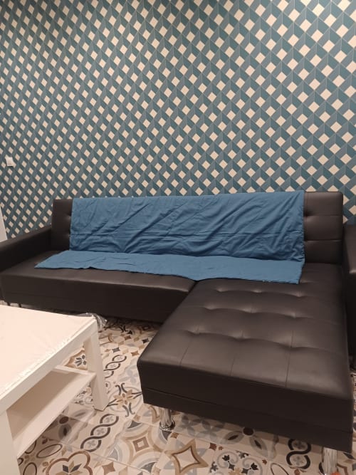 Canapé sectionnel en cuir foncé avec plaid bleu au cottage Accolade, Châteaudun, papier peint à motifs