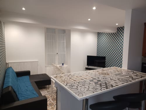 Cottage Accolade à Châteaudun : chambre moderne au mur à motifs géométriques et séjour avec canapé bleu
