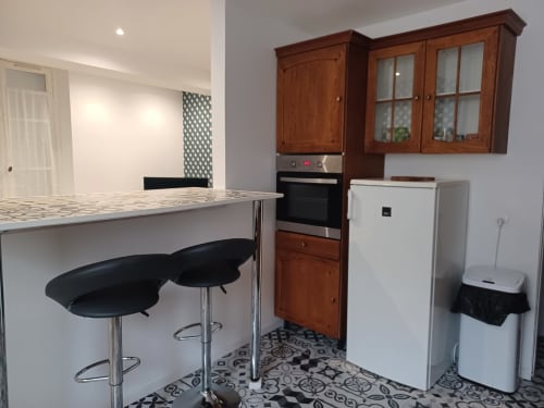 Cuisine moderne du gîte Accolade à Châteaudun avec îlot de cuisine, placards en bois et sol à motifs noirs