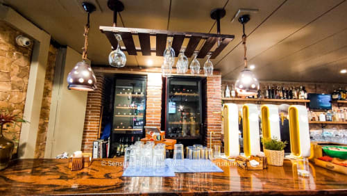 Moderno bar del hotel Gestyp-AT Mérida con mostrador de madera, lámparas colgantes, estantes de vidrio y detalles de ladrillo