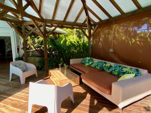 Espace de détente sous pergola en bois aux Villas aux Antilles avec mobilier blanc moderne, canapé marron avec coussins, ambiance tropicale