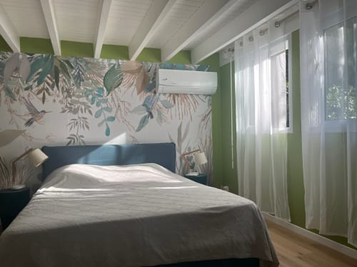 Chambre moderne aux Villas aux Antilles avec lit sombre, papier peint botanique, murs verts, poutres blanches et climatisation
