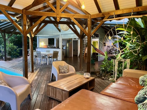 Terrasse couverte avec sièges confortables, table à manger et plantes tropicales luxuriantes aux Villas aux Antilles, Saint-François