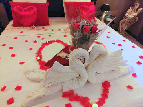 Chambre romantique avec cygnes en serviettes, pétales de rose et décoration cœurs à la suite Love de Les Secrets de Winna en Deux-Sèvres
