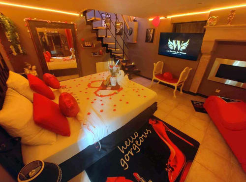 Suite romantique aux Secrets de Winna avec décor rouge et jaune, lit en forme de cœur et éclairage ambiant
