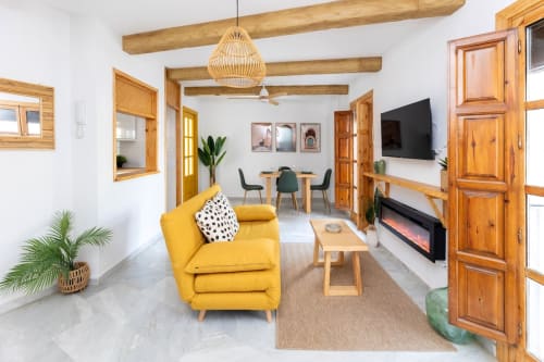 Salón amplio con sofá amarillo, chimenea eléctrica y comedor moderno en apartamento turístico de Granada centro.