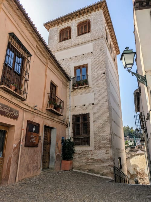 Fachada del Palacio del Conde de Cabra en una calle empedrada del Albaicín, rodeada de arquitectura tradicional en Granada.
