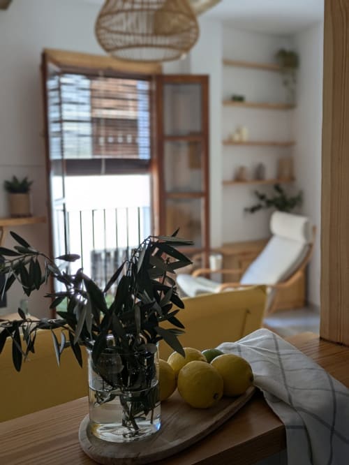 Detalle de mesa con limones, ramas de olivo y decoración en un salón luminoso de apartamento turístico en Granada.