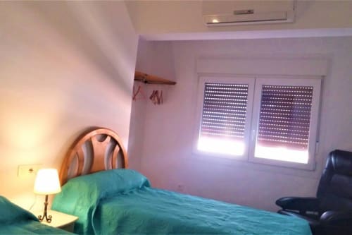 Habitación doble iluminada, con camas individuales y detalles funcionales para una estancia confortable.