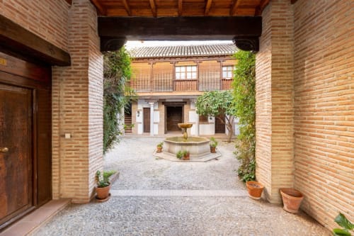 Acogedor patio andaluz con fuente y vegetación, un ambiente perfecto para relajarse.