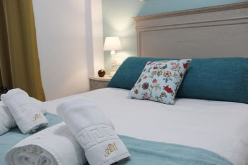 Un dormitorio acogedor con una cama blanca decorada con cojines y toallas perfectamente dobladas, creando un ambiente relajante.