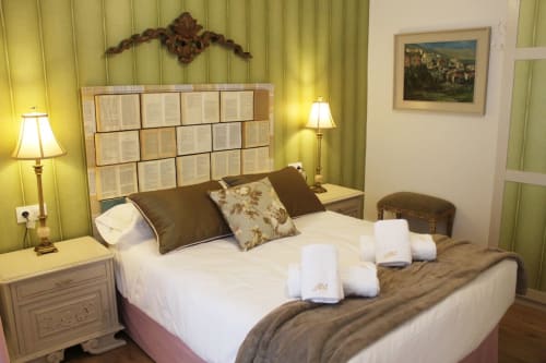 Habitación con cabecero de libros, cama decorada con cojines florales, iluminación cálida y detalles clásicos.