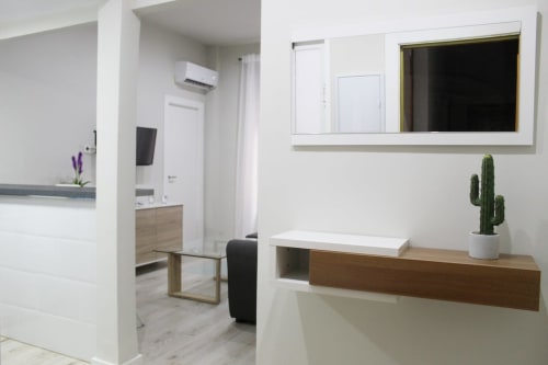 Espacio minimalista con espejo, mueble moderno, cactus decorativo y vista al salón con diseño luminoso y elegante.