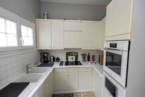 Cuisine crème avec électroménagers en acier inoxydable au gîte Accolade, Châteaudun, comptoirs blancs et carrelage