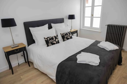 Chambre moderne du gîte Accolade à Châteaudun avec tête de lit foncée, literie blanche et radiateur d'époque