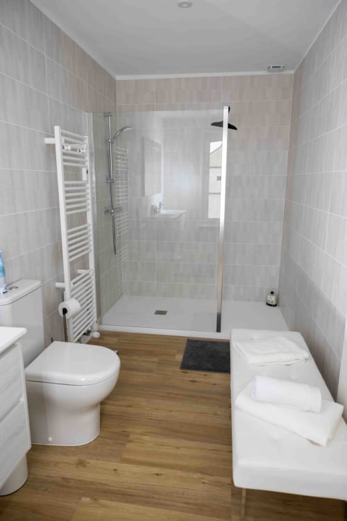 Salle de bains moderne du gîte Accolade à Châteaudun avec douche à l'italienne, sanitaires blancs et sol en bois
