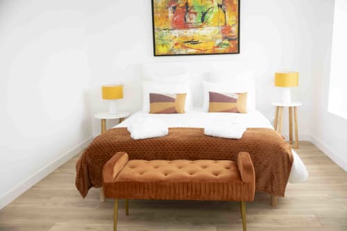 Chambre moderne du Accolade Hotel à Châteaudun avec banc terracotta, touches jaunes et œuvre d'art abstraite