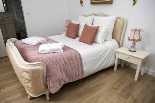 Chambre élégante du cottage Accolade à Châteaudun avec lit crème, accents rose, table de nuit blanche et parquet