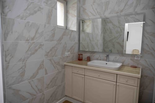 Salle de bain moderne du gîte Accolade à Châteaudun avec carrelage imitation marbre, lavabo et miroir