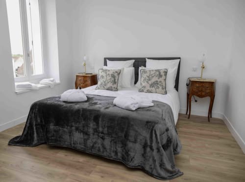 Chambre lumineuse du gîte Accolade à Châteaudun avec jeté en velours noir, literie blanche, oreillers à motifs, bois
