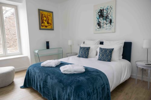Chambre moderne du gîte Accolade à Châteaudun avec accents turquoise, literie blanche et vue sur les monuments