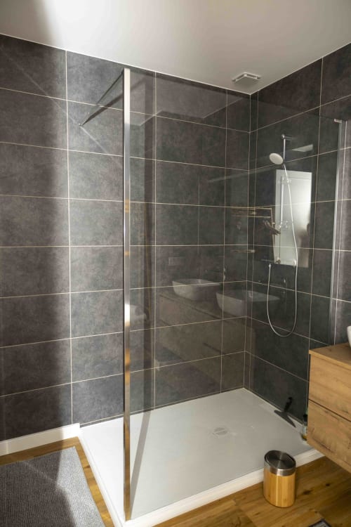 Douche moderne avec paroi vitrée et murs carrelés anthracite au gîte Accolade à Châteaudun