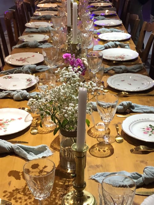 Elegante mesa de comedor formal en Domaine de l'Ocrerie con platos florales, velas blancas y un centro de flores púrpura