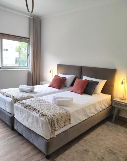 Spacious bedroom at Embaixada da Vila B&B in Cascais with modern bed, burgundy pillows, and warm lighting