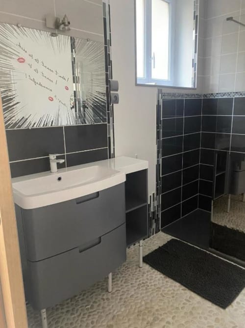 Salle de bain moderne aux Gîtes de Flo avec lavabo gris, douche carrelée noire et sol à motifs à Saint Ennemond