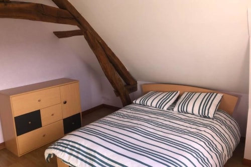 Chambre douillette à la villa Les gîtes de Flo avec literie rayée, poutres en bois et mobilier rustique