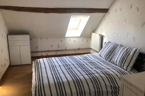 Chambre mansardée cosy aux Gîtes de Flo avec literie rayée, lucarne et vue sur le jardin