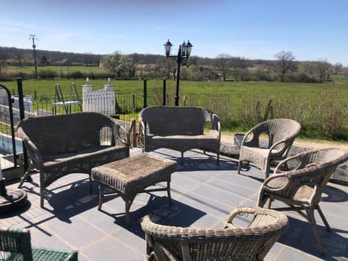 Coin salon en terrasse avec mobilier en osier donnant sur les jardins verdoyants de la villa Les gîtes de Flo à Saint Ennemond