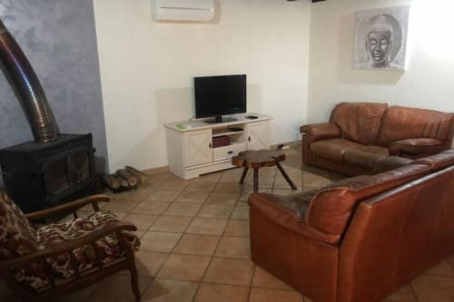 Salon cosy de la villa aux gîtes de Flo avec sièges en cuir, cheminée et TV à Saint Ennemond