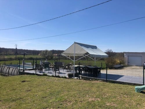 Auvent à rayures et espace repas aux gîtes de Flo à Saint Ennemond, vue sur le jardin