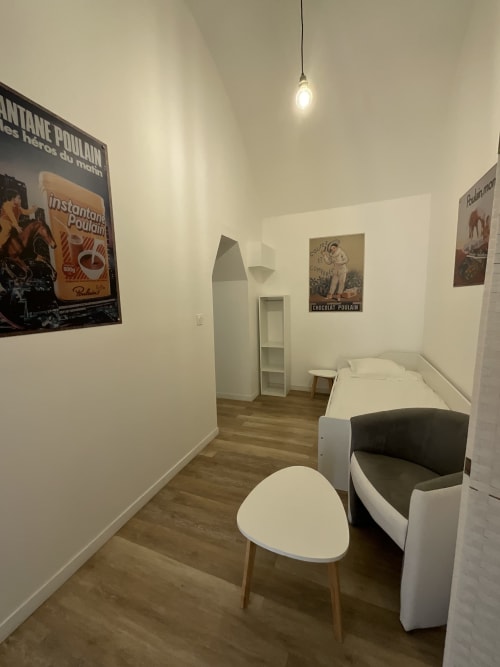 Cozy cottage room at Locacharme Blois with bed, chair, vintage posters, and wooden flooring