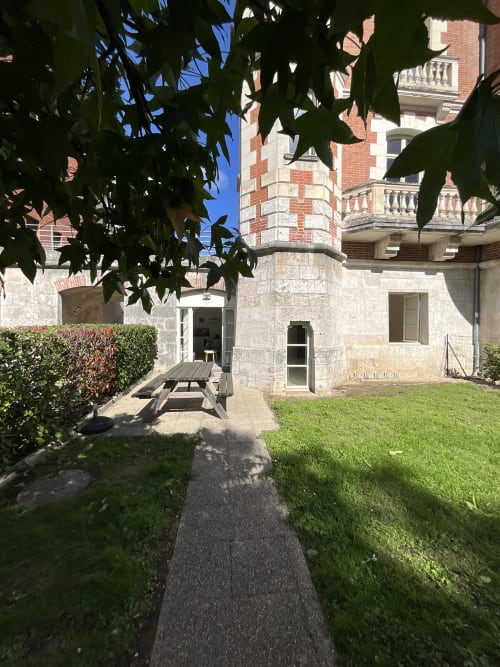 Garden courtyard entrance of Locacharme cottage in Blois with stone walls and green lawn