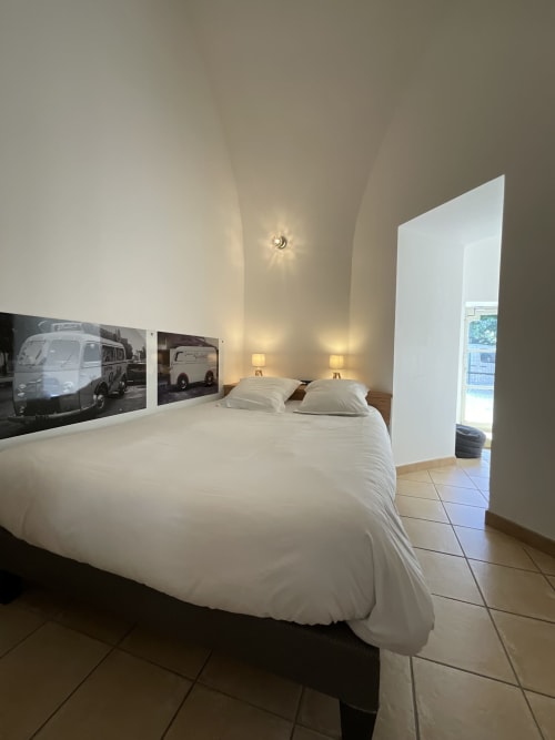 Modern bedroom in Locacharme cottage, Blois, with white bedding, vintage caravan wall art, and garden view access
